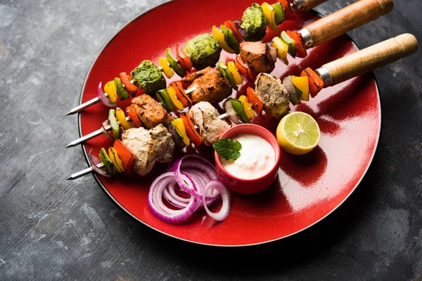 Hariyali kakab tavuk mu ile hizmet Malai malai Kebap şişleri ve yoğurt dip bir tabak içinde. seçici odak