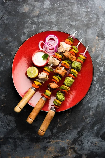 Hariyali kakab tavuk mu ile hizmet Malai malai Kebap şişleri ve yoğurt dip bir tabak içinde. seçici odak