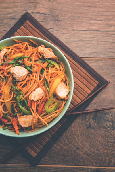 Chicken Hakka/Schezwan noodles served in a bowl with chopsticks. selective focus