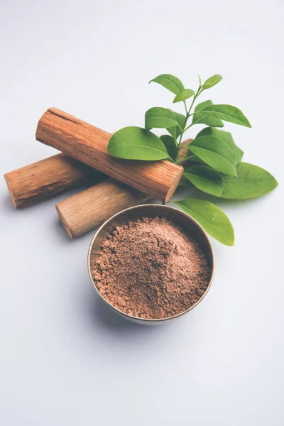 Chandan or sandalwood powder with sticks and green leaves