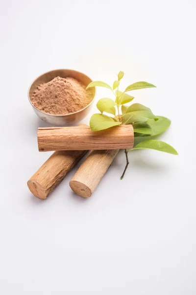 Chandan or sandalwood powder with sticks and green leaves