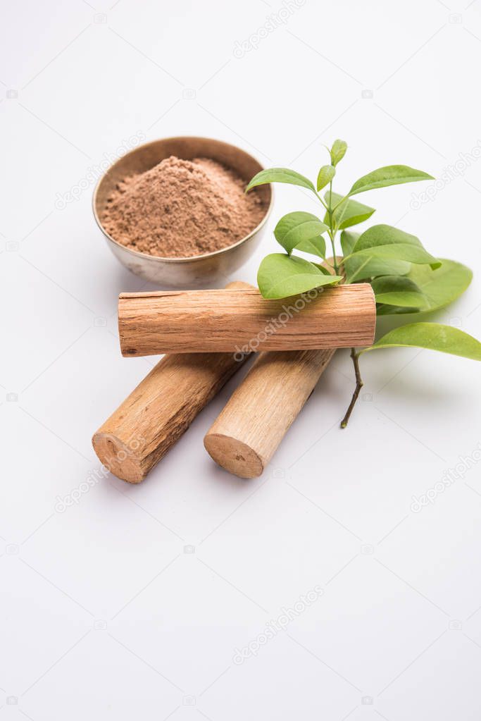 Chandan or sandalwood powder with sticks and green leaves