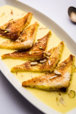 shahi tukra/tukda veya Double ka meetha kuru meyve, seçici odak ile süslenmiş kuduz veya tatlı safran süt batırılmış kızarmış ekmek dilimleri hint tatlı bir ekmek puding