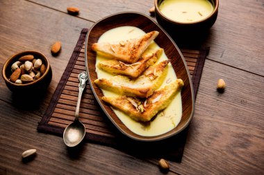 shahi tukra/tukda veya Double ka meetha kuru meyve, seçici odak ile süslenmiş kuduz veya tatlı safran süt batırılmış kızarmış ekmek dilimleri hint tatlı bir ekmek puding
