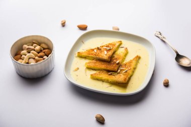 shahi tukra/tukda veya Double ka meetha kuru meyve, seçici odak ile süslenmiş kuduz veya tatlı safran süt batırılmış kızarmış ekmek dilimleri hint tatlı bir ekmek puding