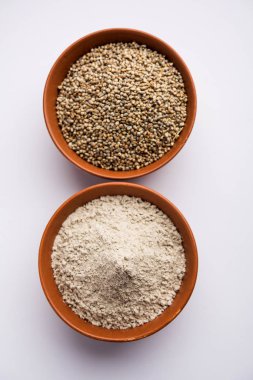 Bajra (inci darı)/bir kasede onun un veya tozu ile sorgum taneleri, seçici odak