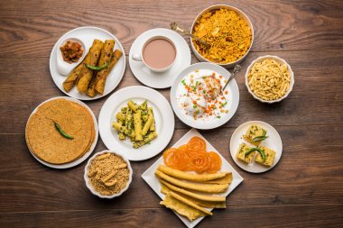 Group of Gujarati snacks like jalebi-fafda, thepla, khaman dhokla, aloo bhujiya, khandvi,khakra, dahi vada, gathiya with hot tea clipart