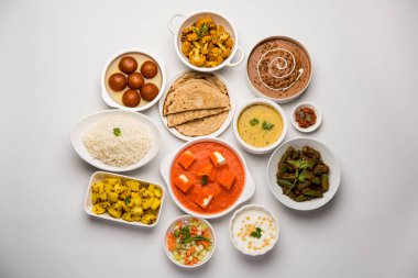 Paneer tereyağı masala, dal makhani, roti, pirinç, sabji, gulab jamun ve bağlı raita gibi çeşitli Hint gıda karamsar arka plan, seçici odak üzerinde kaselerde servis