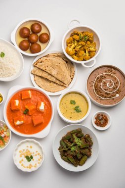 Paneer tereyağı masala, dal makhani, roti, pirinç, sabji, gulab jamun ve bağlı raita gibi çeşitli Hint gıda karamsar arka plan, seçici odak üzerinde kaselerde servis