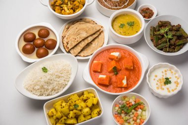 Paneer tereyağı masala, dal makhani, roti, pirinç, sabji, gulab jamun ve bağlı raita gibi çeşitli Hint gıda karamsar arka plan, seçici odak üzerinde kaselerde servis