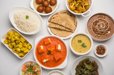 Paneer tereyağı masala, dal makhani, roti, pirinç, sabji, gulab jamun ve bağlı raita gibi çeşitli Hint gıda karamsar arka plan, seçici odak üzerinde kaselerde servis