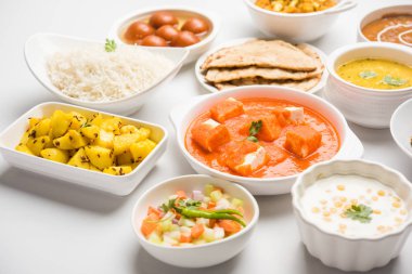 Paneer tereyağı masala, dal makhani, roti, pirinç, sabji, gulab jamun ve bağlı raita gibi çeşitli Hint gıda karamsar arka plan, seçici odak üzerinde kaselerde servis