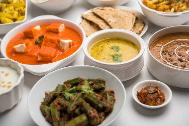 Paneer tereyağı masala, dal makhani, roti, pirinç, sabji, gulab jamun ve bağlı raita gibi çeşitli Hint gıda karamsar arka plan, seçici odak üzerinde kaselerde servis