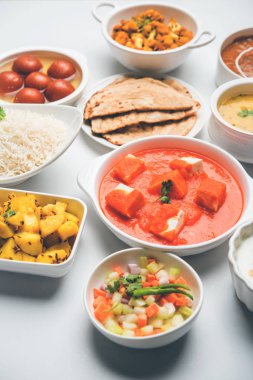 Paneer tereyağı masala, dal makhani, roti, pirinç, sabji, gulab jamun ve bağlı raita gibi çeşitli Hint gıda karamsar arka plan, seçici odak üzerinde kaselerde servis