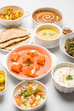Paneer tereyağı masala, dal makhani, roti, pirinç, sabji, gulab jamun ve bağlı raita gibi çeşitli Hint gıda karamsar arka plan, seçici odak üzerinde kaselerde servis