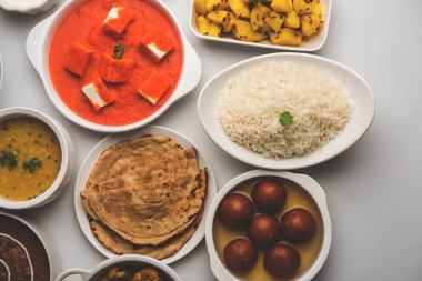 Paneer tereyağı masala, dal makhani, roti, pirinç, sabji, gulab jamun ve bağlı raita gibi çeşitli Hint gıda karamsar arka plan, seçici odak üzerinde kaselerde servis