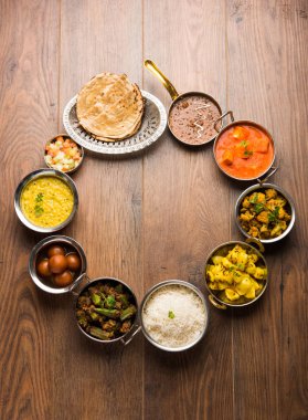 Paneer tereyağı masala, dal makhani, roti, pirinç, sabji, gulab jamun ve bağlı raita gibi çeşitli Hint gıda karamsar arka plan, seçici odak üzerinde kaselerde servis