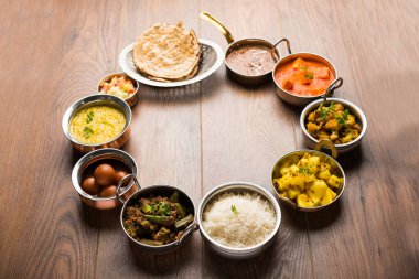 Paneer tereyağı masala, dal makhani, roti, pirinç, sabji, gulab jamun ve bağlı raita gibi çeşitli Hint gıda karamsar arka plan, seçici odak üzerinde kaselerde servis