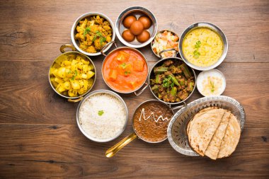Paneer tereyağı masala, dal makhani, roti, pirinç, sabji, gulab jamun ve bağlı raita gibi çeşitli Hint gıda karamsar arka plan, seçici odak üzerinde kaselerde servis