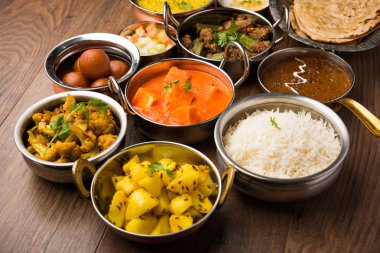 Paneer tereyağı masala, dal makhani, roti, pirinç, sabji, gulab jamun ve bağlı raita gibi çeşitli Hint gıda karamsar arka plan, seçici odak üzerinde kaselerde servis