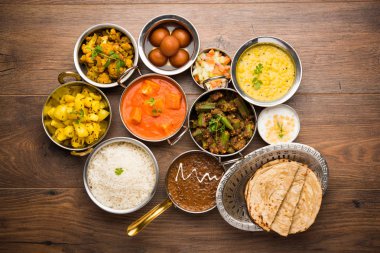 Paneer tereyağı masala, dal makhani, roti, pirinç, sabji, gulab jamun ve bağlı raita gibi çeşitli Hint gıda karamsar arka plan, seçici odak üzerinde kaselerde servis