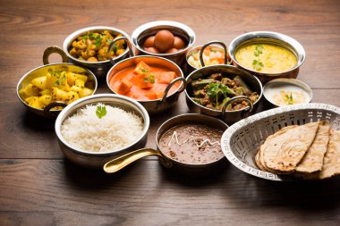 Paneer tereyağı masala, dal makhani, roti, pirinç, sabji, gulab jamun ve bağlı raita gibi çeşitli Hint gıda karamsar arka plan, seçici odak üzerinde kaselerde servis