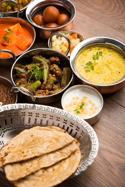 パナーバターマサラ ダルマカニ ロティ ライス サブジ グラブジャマン バウンドライタのような様々なインド料理は ムーディーな背景の上にボウルで提供され 選択的な焦点 — ストック写真