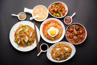 Assorted Indo chinese food in group includes non vegetarian or chicken Schezwan/Szechuan hakka noodles, fried rice, manchurian, egg american chop suey, soup with spoon and chop sticks, selective focus clipart