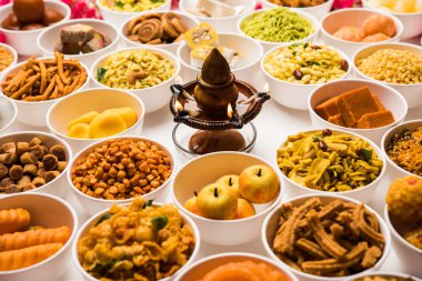 Beyaz arka plan üzerinde diya ile Diwali için kase tatlılar ve Farsan / aperatifler Rangoli