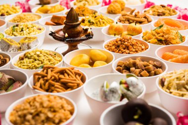 Beyaz arka plan üzerinde diya ile Diwali için kase tatlılar ve Farsan / aperatifler Rangoli