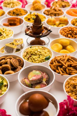 Beyaz arka plan üzerinde diya ile Diwali için kase tatlılar ve Farsan / aperatifler Rangoli