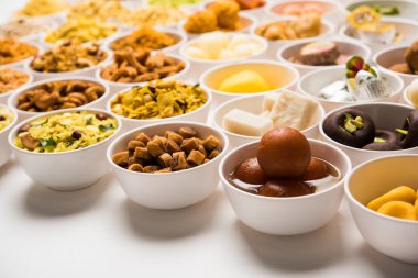 Beyaz arka plan üzerinde diya ile Diwali için kase tatlılar ve Farsan / aperatifler Rangoli