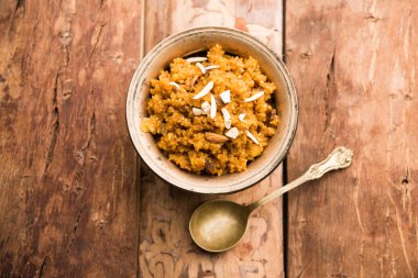 Wheat Laapsi/Lapsi/Shira/Halwa is an Indian sweet dish made of broken wheat or Daliya pieces and ghee along with nuts, raisins and dried fruits. It's a healthy food. served in a bowl, selective focus clipart