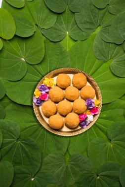 Indian Festival Dussehra, symbolic Golden or Piliostigma leaf or Bauhinia racemosa also known as Apta patti, arranged in circular pattern with Bundi or motichoor laddu served in plate at centre clipart