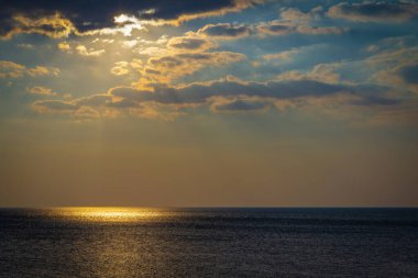 Parlak ay ve bulutlu deniz manzarası. Deniz yüzeyindeki ışığın altın yansıması.