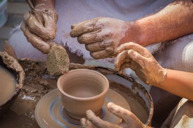 Usta çömlekçinin elleri çömlekçiliğin sırlarını açığa çıkarır ve çömlek yapımında öğrencinin ellerine rehberlik eder..