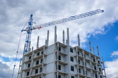 Bulutlu bir gökyüzüne karşı bir binanın önünde inşaat vinci