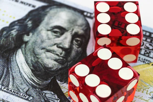 İki kırmızı zar yan yana Benjamin Franklin 'in portresiyle bulanık banknotların üzerinde yatıyor, üst görünüm / 6 ve 6, kumar konsepti.
