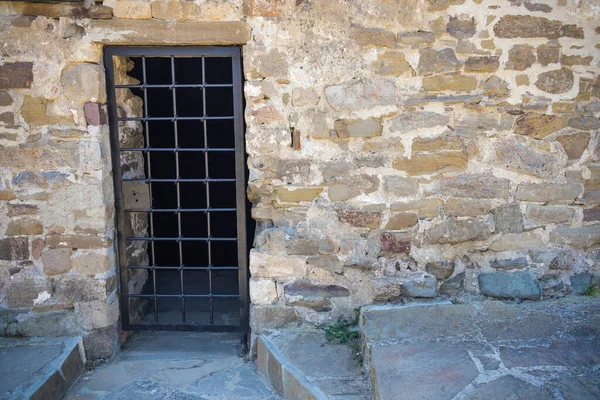Taş duvarda metal ızgarası olan bir geçit.