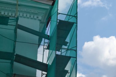 Eski bina restorasyon altında, güvenlik için yeşil ağa sarılmış.