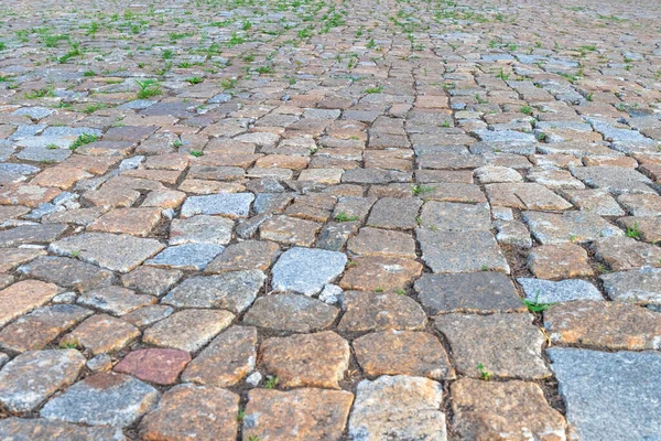 Cobblestone road with grass. Texture of old rural road, bottom view.