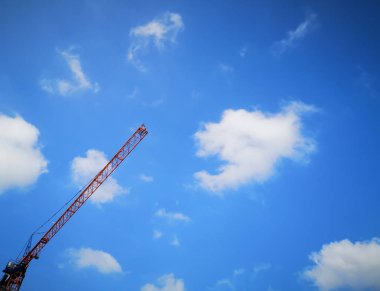 Bulutlu bir mavi gökyüzü karşı bir kırmızı İnşaat Vinç kolu