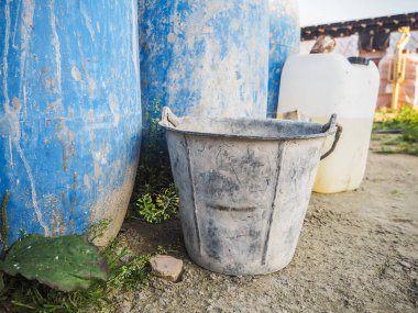Mavi plastik varil ve bir inşaatta kullanılan metal kova
