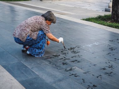 Beijing, Çin - Eylül 2017: su hat Çince karakterler anında yok olur ve okunabilir değildir ısı nedeniyle ama pratik yaşlı kadın