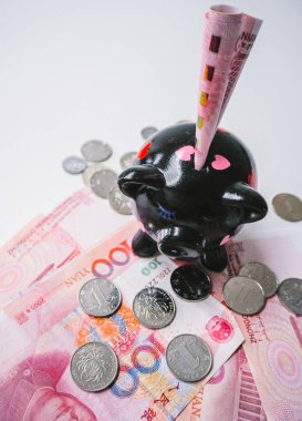 Çin 100 rmb banknot ve madeni paraların Beyaz ahşap zemin üzerinde siyah kumbara ayakta. Domuz sembol servet Çince Zodyak.