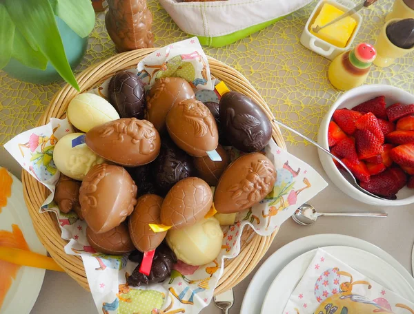 Easter brunch flat lay table setting with chocolate eggs in a basket, strawberries, butter, etc