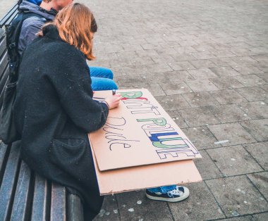Genç kadın el yapımı bir poster olarak eylem iklim hareketi gençlik iklim değişikliğine karşı bir protesto yürüyüşü sırasında bir arama yapma
