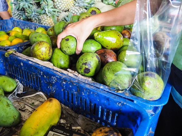 Person purchasing green fresh avocado\'s in a local shop