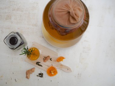 Beyaz arka planda narenciye, gülerkaptan ve biberiye aromalı Kombucha çayı ile cam