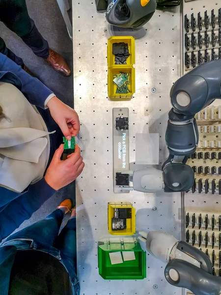 Operadora caucásica de pie en una estación de trabajo de montaje con un robot colaborativo — Foto de Stock